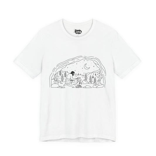 White tee with black line-art caveman scene inside a cave arch under a moon